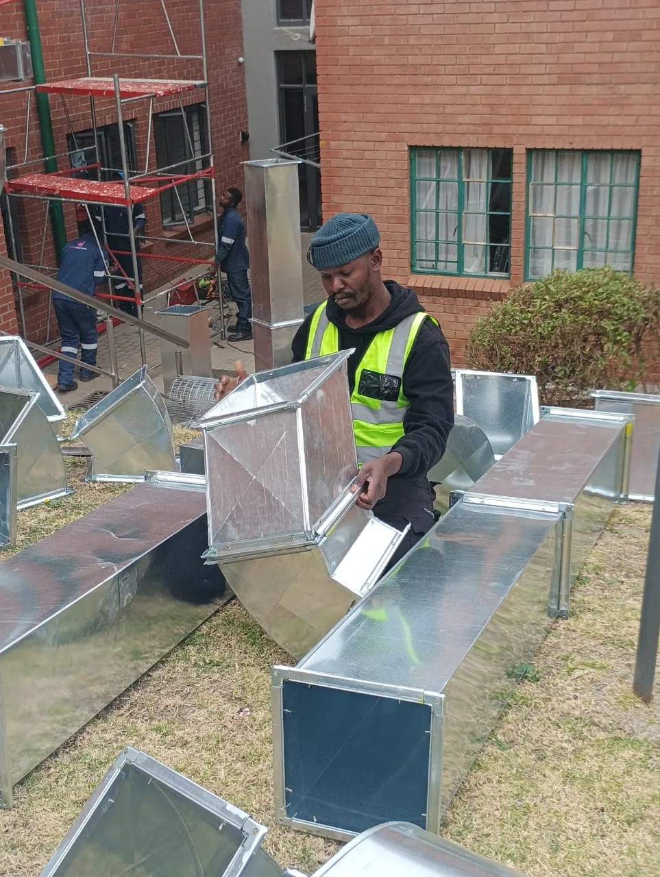 Technician handling fabricated ventilation duct sections