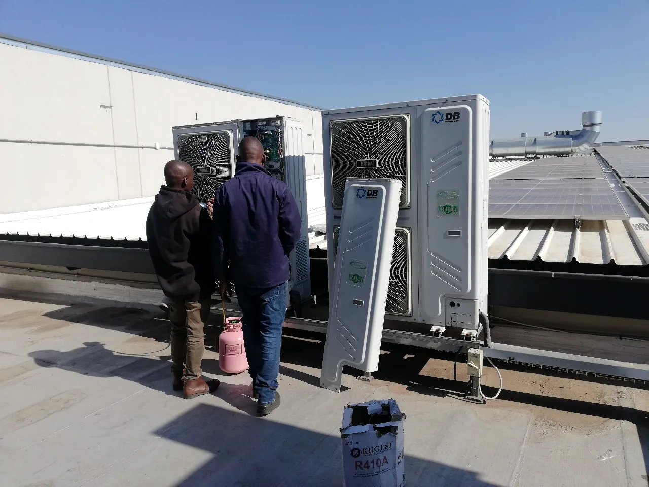 Technicians servicing commercial rooftop air-conditioning equipment