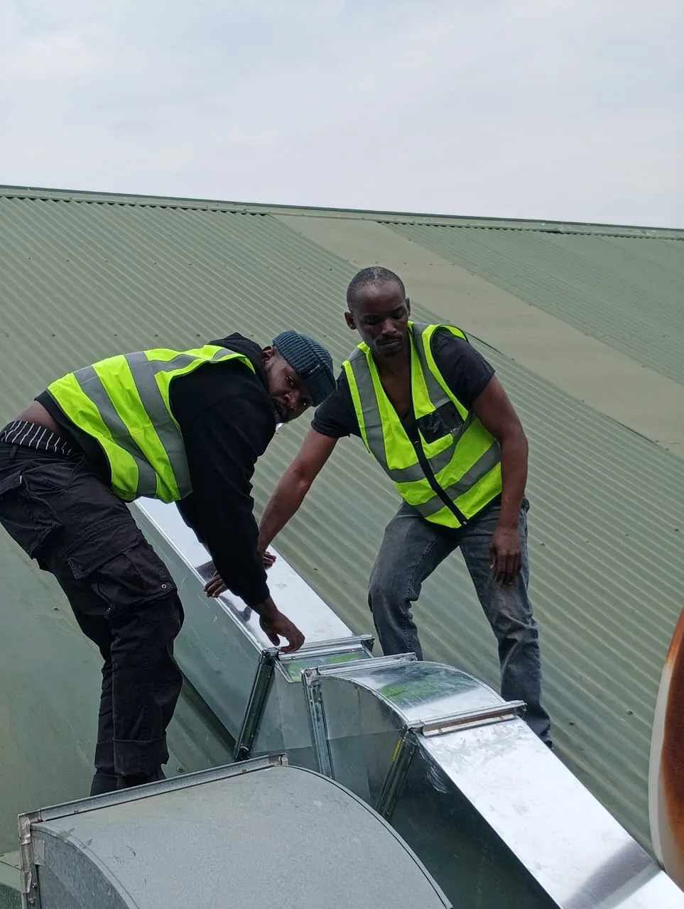 Technicians joining rooftop ventilation ductwork