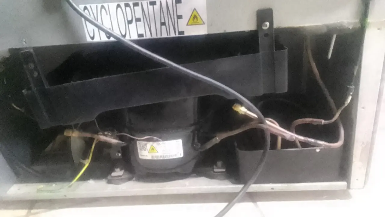 Open rear section of a refrigerator showing compressor and refrigeration components during service